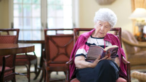 old woman sitting in chair reading