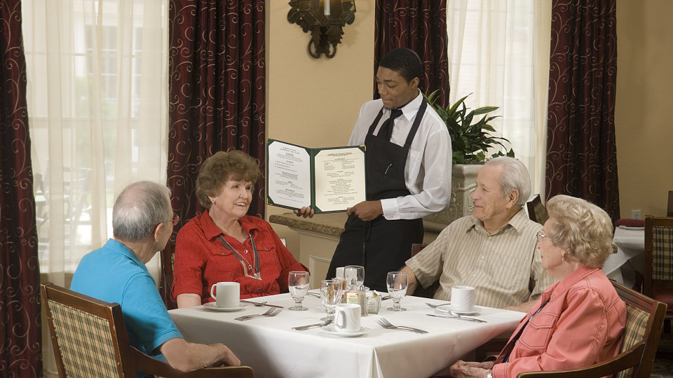 waiter showing menu to seniors in dining room