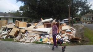 old woman standing in front of pile of garbage