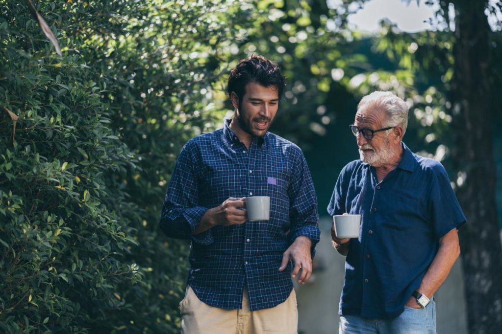 two people walk and drink coffee talking about moving a parent into senior memory care