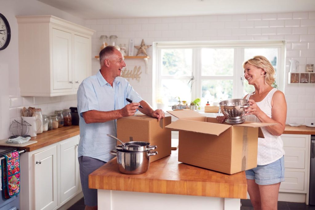 two elderly people pack a box possibly downsizing for retirement