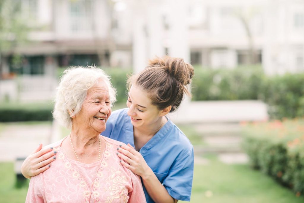 healthcare worker hugs an elderly person during part of the continuum of care for seniors