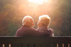 two seniors sit on a bench in a retirement community for senior couples