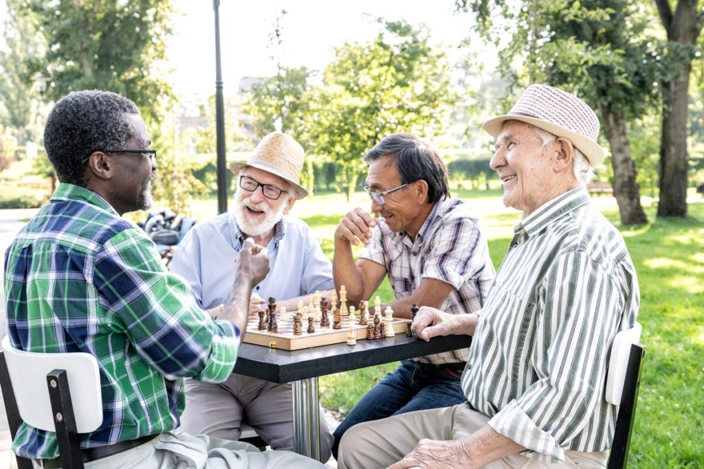 a group of seniors with limited mobility play chess outdoors