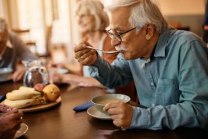 a senior eats soup possibly after learning the link between diet and dementia