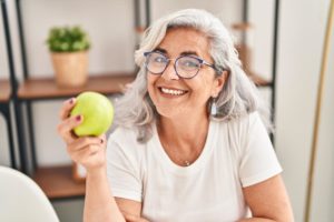 a person holds an apple after researching heart healthy foods for seniors