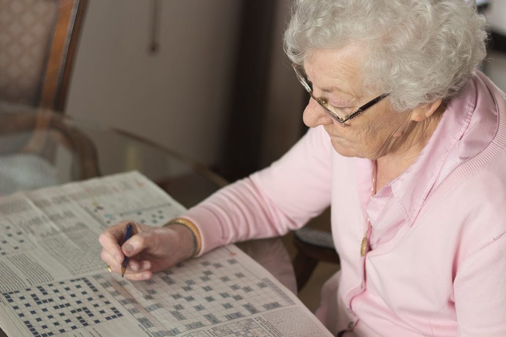 Woman doing a crossword puzzle in a senior memory care program