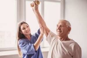 Man in senior living facility with caregiver and enjoying the benefits of senior physical therapy