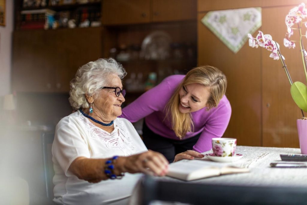 Elderly woman and caregiver smiling while discussing reasons for skilled nursing