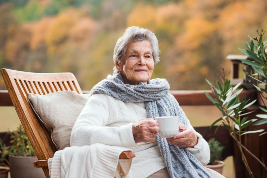 Elderly woman enjoying cup of tea outdoors and considering respite care