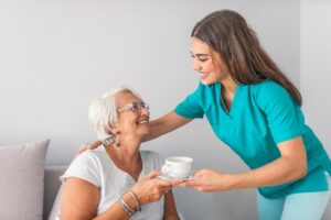 Nurse gives senior a cup of tea, as they discuss the benefits of assisted living for seniors