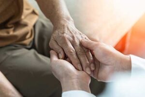 Caretaker holding a patient's hand in senior memory care
