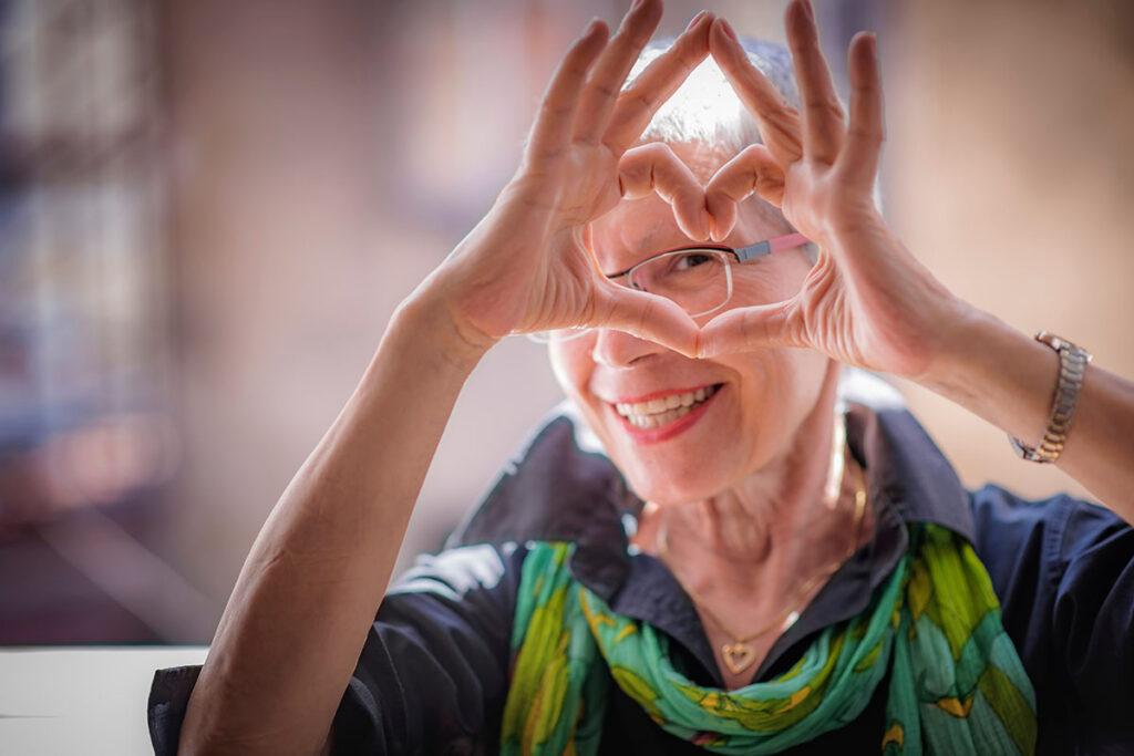 senior adult making a heart with her hands after reading assisted living faq