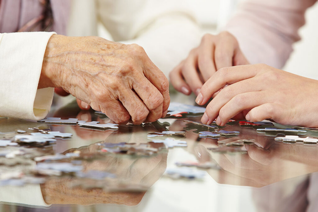 seniors in memory care completing puzzle together after paying memory care costs in austin tx