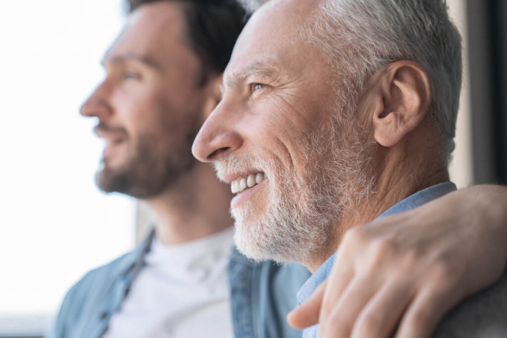 son with arm around father while helping with the challenges of memory care for families